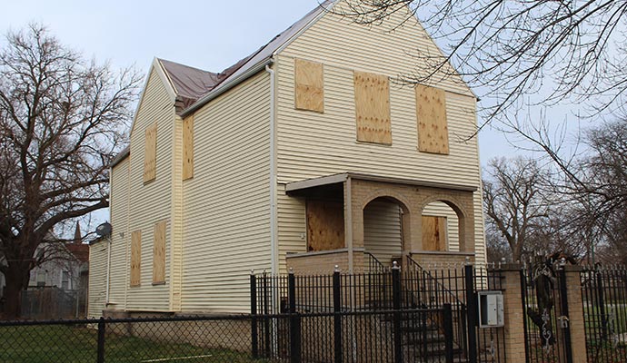 Boarded up house with roof tarp
