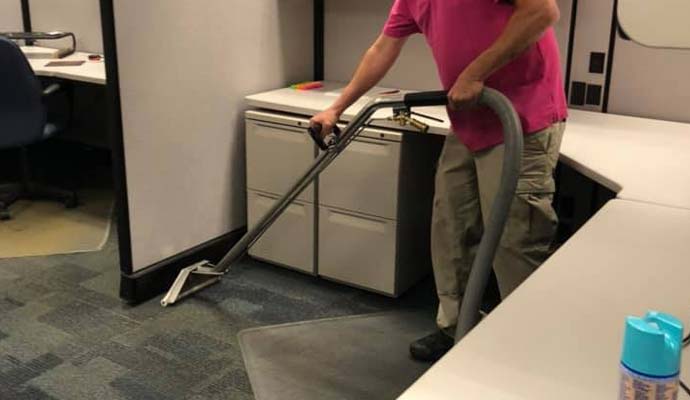 A person is deep cleaning carpet in office