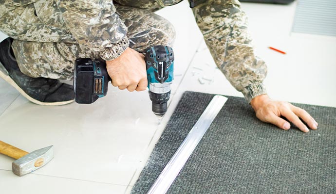 A person installing metal carpet transition strip