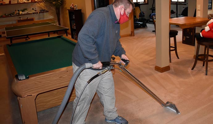 Professional worker performing carpet cleaning with specialized equipment.