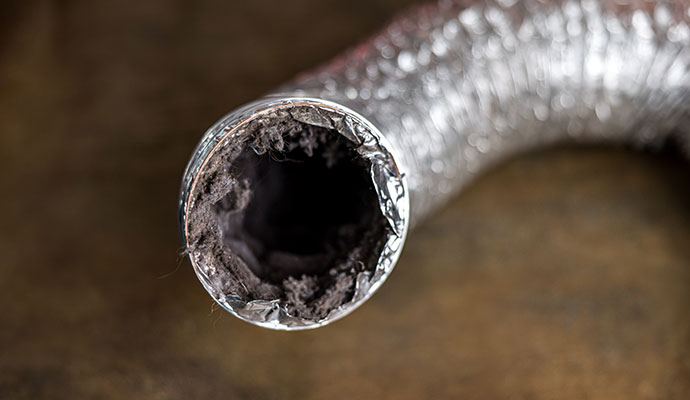 Interior view of a flexible dryer vent hose heavily clogged with thick layers of lint and debris