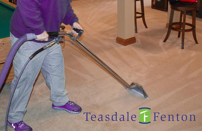 Professional worker performing carpet cleaning with specialized equipment.