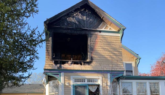 Home exterior with visible fire and smoke damage on upper level