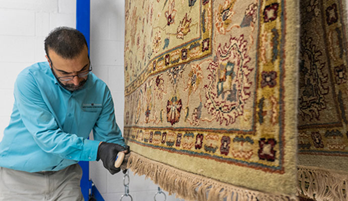 Specialist brushing fringe of hanging oriental area rug