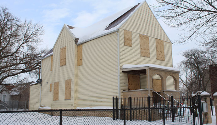 House exterior with plywood covering windows in winter