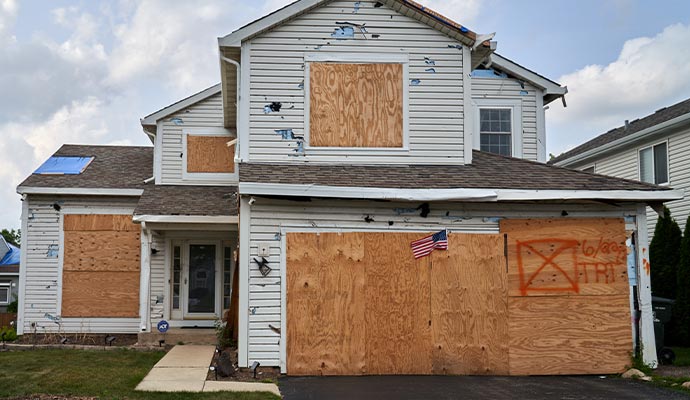A boarded-up hail and storm damaged residential house