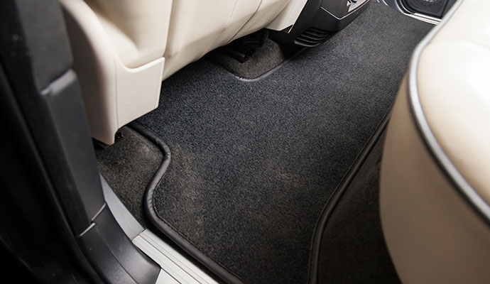 Black floor mat with visible dirt and dust positioned in the rear footwell