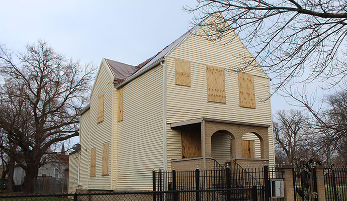 Two-story house with plywood boards covering all windows and doors for emergency property protection