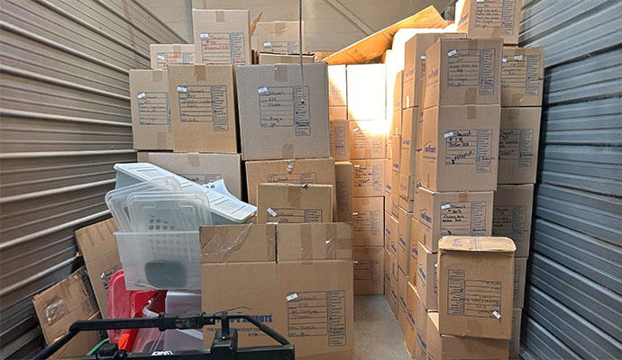 Storage unit filled with stacked cardboard boxes containing personal belongings during a pack-out service