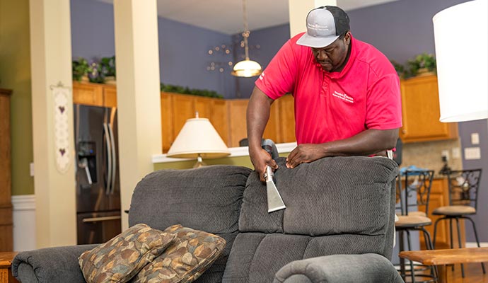 Technician cleaning sofa upholstery with extraction tool