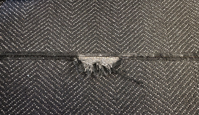 Torn and frayed seam in dark patterned carpet